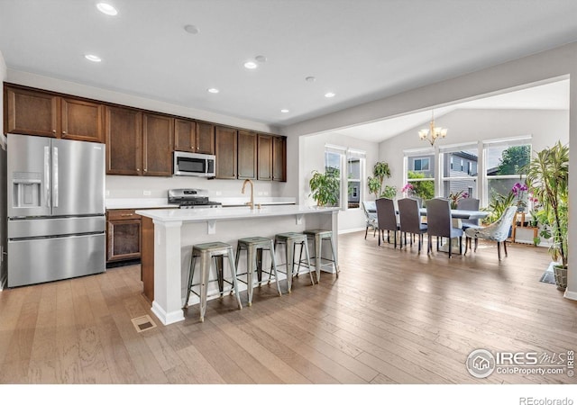 6244 Waterman Way, Frederick, CO 80516 - kitchen featuring appliances with stainless steel finishes, a chandelier, light countertops, a kitchen bar, and a kitchen island with sink