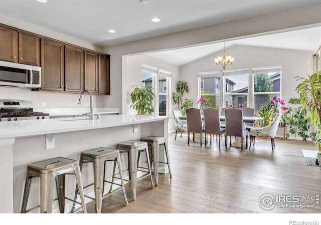 6244 Waterman Way, Frederick, CO 80516 - kitchen featuring stainless steel appliances, lofted ceiling, a breakfast bar area, light wood-style floors, and a chandelier