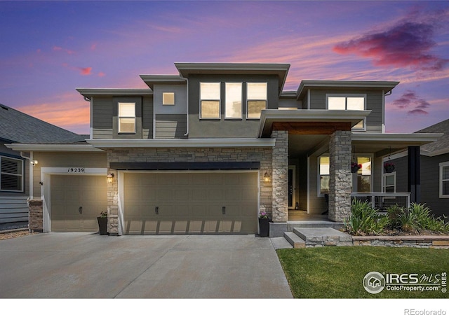 19239 W 88th Dr, Arvada, CO 80007 - modern home with concrete driveway, stone siding, a porch, and a garage