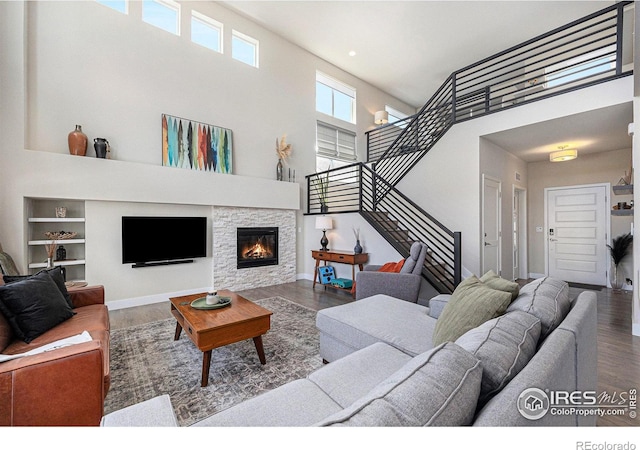 19239 W 88th Dr, Arvada, CO 80007 - living area featuring wood finished floors, a towering ceiling, stairs, a stone fireplace, and recessed lighting