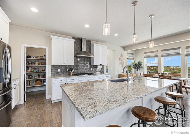 19239 W 88th Dr, Arvada, CO 80007 - kitchen with wall chimney range hood, stainless steel appliances, dark wood-type flooring, a kitchen breakfast bar, and recessed lighting