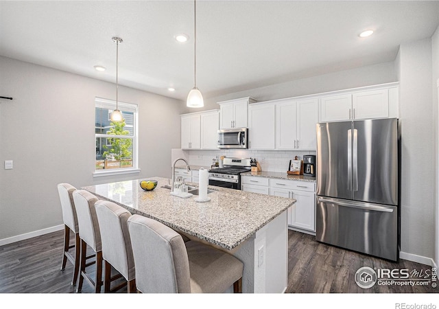 7415 E 158th Pl, Thornton, CO 80602 - kitchen with appliances with stainless steel finishes, an island with sink, dark wood-type flooring, white cabinetry, and recessed lighting