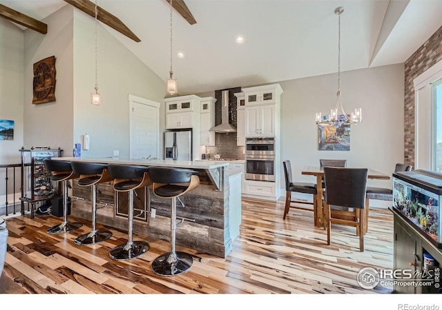 5279 Long Dr, Timnath, CO 80547 - kitchen featuring stainless steel appliances, wall chimney range hood, light wood-type flooring, a kitchen breakfast bar, and white cabinets