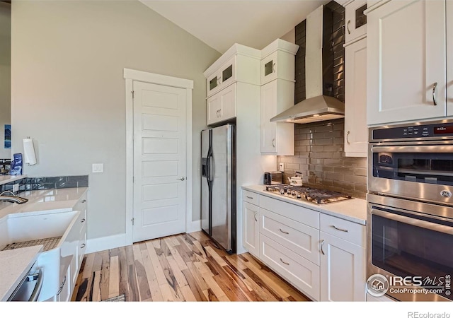 5279 Long Dr, Timnath, CO 80547 - kitchen with appliances with stainless steel finishes, wall chimney exhaust hood, light wood-style flooring, lofted ceiling, and decorative backsplash