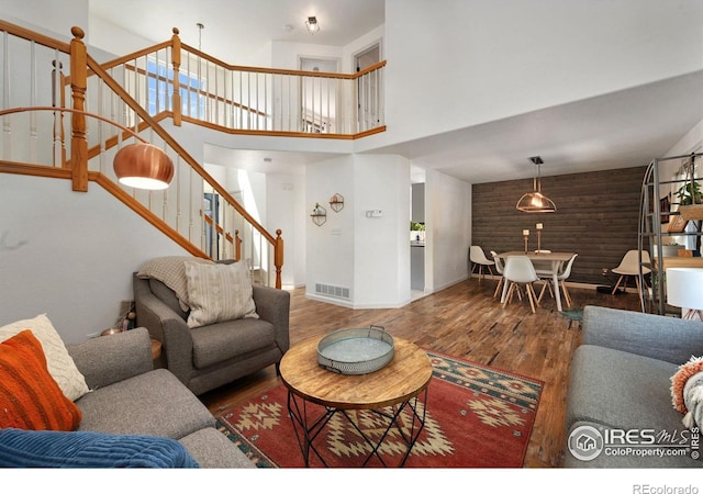 6836 Timpas Dr, Fort Collins, CO 80525 - living room featuring wood finished floors, stairs, a towering ceiling, and wooden walls