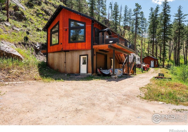 200 Falls Creek Dr, Bellvue, CO 80512 - view of front of property with stairway, a wooden deck, dirt driveway, an outbuilding, and an attached garage