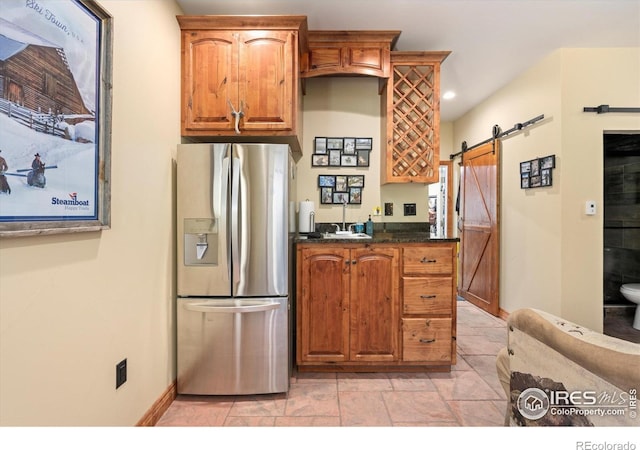200 Falls Creek Dr, Bellvue, CO 80512 - kitchen featuring stainless steel fridge, a barn door, brown cabinetry, dark stone countertops, and recessed lighting