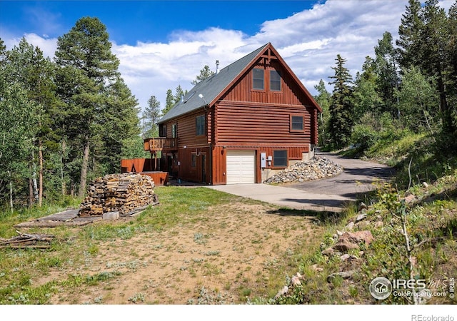 280 Hummer Dr, Nederland, CO 80466 - view of side of property featuring an attached garage, board and batten siding, log exterior, driveway, and a deck