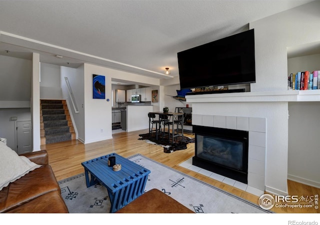 3970 Colorado Ave Unit G, Boulder, CO 80303 - living area featuring stairway, a tiled fireplace, and wood finished floors