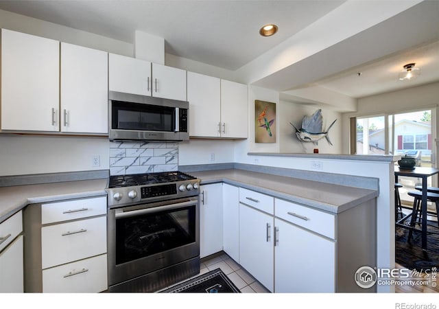 3970 Colorado Ave Unit G, Boulder, CO 80303 - kitchen featuring appliances with stainless steel finishes, a peninsula, white cabinetry, recessed lighting, and light tile patterned flooring