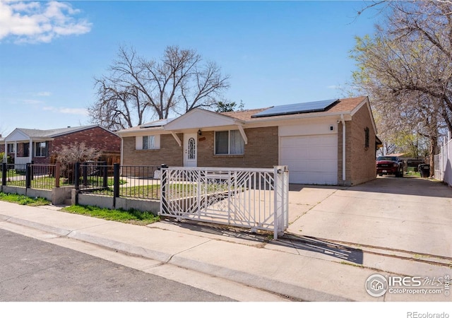 5519 Tucson St, Denver, CO 80239 - ranch-style house with brick siding, concrete driveway, an attached garage, a fenced front yard, and roof mounted solar panels