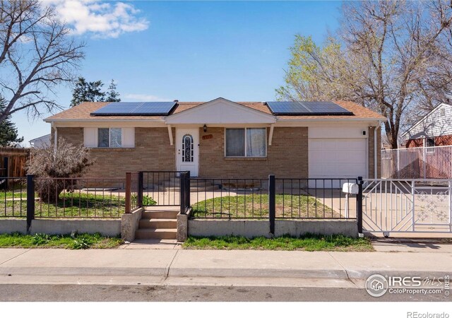 5519 Tucson St, Denver, CO 80239 - ranch-style home featuring brick siding, a garage, a fenced front yard, and roof mounted solar panels