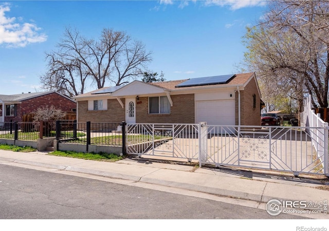 5519 Tucson St, Denver, CO 80239 - ranch-style house featuring brick siding, an attached garage, a fenced front yard, solar panels, and concrete driveway