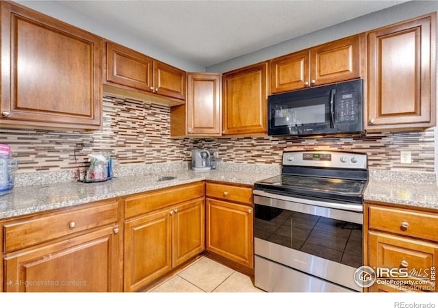 5519 Tucson St, Denver, CO 80239 - kitchen featuring black microwave, stainless steel range with electric stovetop, light tile patterned floors, and brown cabinetry