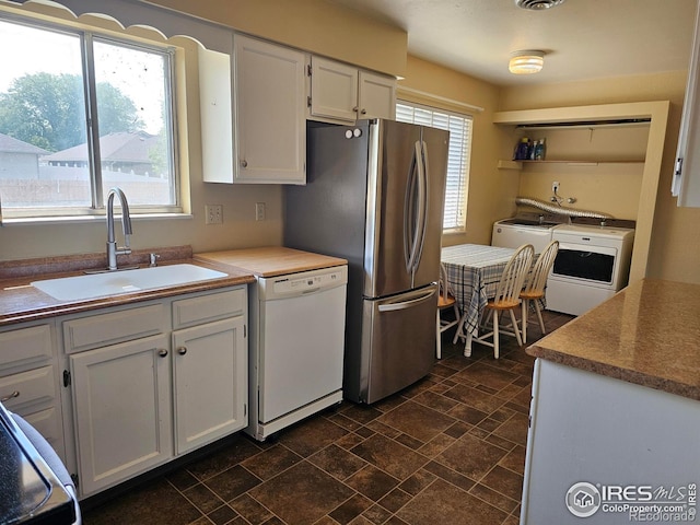 1402 Fillmore St, Sterling, CO 80751 - kitchen featuring dishwasher, freestanding refrigerator, washer and dryer, white cabinetry, and dark stone finish flooring