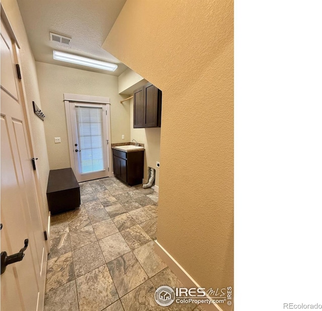 2110 Nancy Gray Ave, Fort Collins, CO 80525 - laundry room featuring a textured wall, light stone finish flooring, and cabinet space