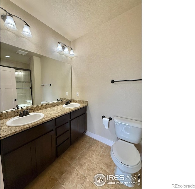 2110 Nancy Gray Ave, Fort Collins, CO 80525 - full bathroom with double vanity, an enclosed shower, a textured ceiling, and tile patterned floors