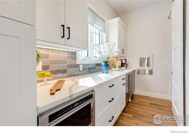 4198 Prestwich Ct, Timnath, CO 80547 - kitchen with tasteful backsplash, white cabinetry, light wood-style flooring, and light stone countertops