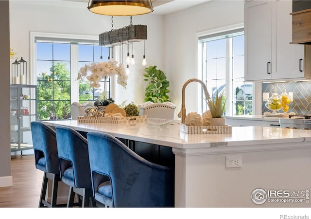 4198 Prestwich Ct, Timnath, CO 80547 - kitchen with backsplash, plenty of natural light, a breakfast bar, and light wood-type flooring
