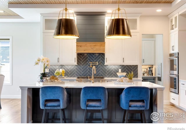 4198 Prestwich Ct, Timnath, CO 80547 - kitchen with double oven, decorative backsplash, a breakfast bar area, and white cabinets