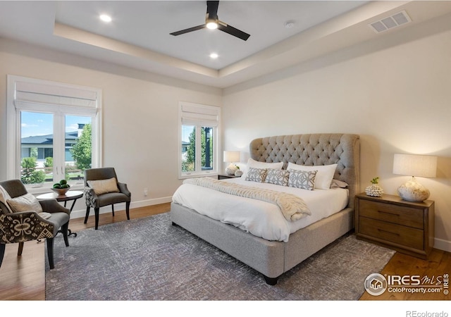 4198 Prestwich Ct, Timnath, CO 80547 - bedroom featuring multiple windows, wood finished floors, a tray ceiling, recessed lighting, and a ceiling fan