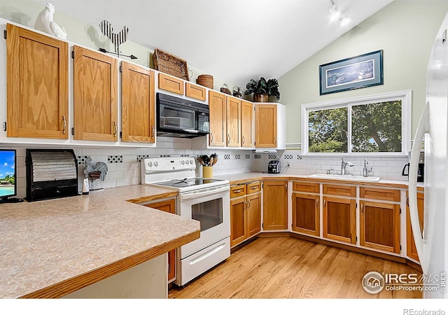 1470 71st Ave, Greeley, CO 80634 - kitchen featuring white appliances, vaulted ceiling, light countertops, light wood-style flooring, and decorative backsplash
