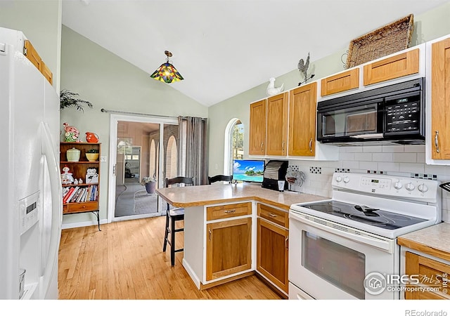 1470 71st Ave, Greeley, CO 80634 - kitchen featuring white appliances, a peninsula, lofted ceiling, light wood-type flooring, and a breakfast bar area