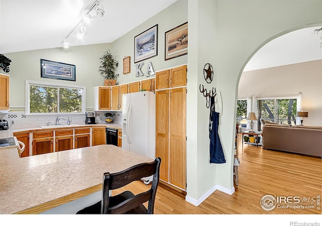 1470 71st Ave, Greeley, CO 80634 - kitchen with white refrigerator with ice dispenser, arched walkways, light wood-style flooring, tasteful backsplash, and high vaulted ceiling