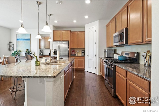 833 Carbonate Ln, Erie, CO 80516 - kitchen with appliances with stainless steel finishes, a breakfast bar, recessed lighting, dark wood-style flooring, and decorative backsplash