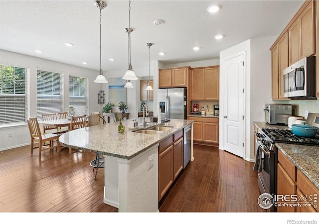 833 Carbonate Ln, Erie, CO 80516 - kitchen with appliances with stainless steel finishes, a breakfast bar, dark wood-style floors, recessed lighting, and hanging light fixtures