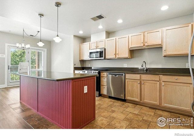 1631 N Emerson St Unit 207, Denver, CO 80218 - kitchen featuring appliances with stainless steel finishes, dark countertops, light brown cabinets, a center island, and a chandelier