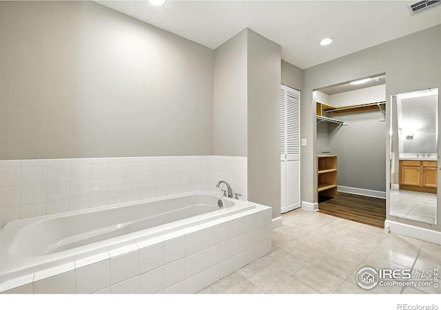 1631 N Emerson St Unit 207, Denver, CO 80218 - bathroom with vanity, a garden tub, tile patterned flooring, a walk in closet, and recessed lighting