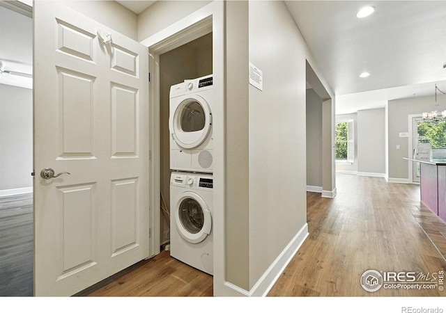 1631 N Emerson St Unit 207, Denver, CO 80218 - washroom featuring estacked washer and dryer, light wood-style floors, a chandelier, and recessed lighting