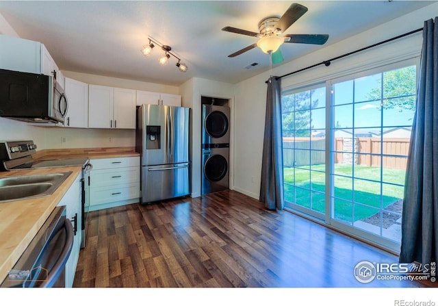 6126 Shamrock Cir, Frederick, CO 80530 - kitchen with stainless steel appliances, estacked washer and dryer, butcher block counters, white cabinets, and ceiling fan