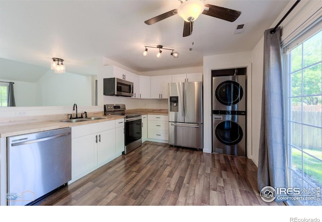 6126 Shamrock Cir, Frederick, CO 80530 - kitchen featuring stainless steel appliances, stacked washer / drying machine, dark wood-style flooring, light countertops, and white cabinets