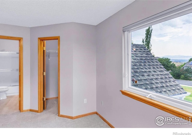 147 Keystone Trl, Broomfield, CO 80020 - unfurnished bedroom featuring multiple windows, a spacious closet, light carpet, a textured ceiling, and connected bathroom