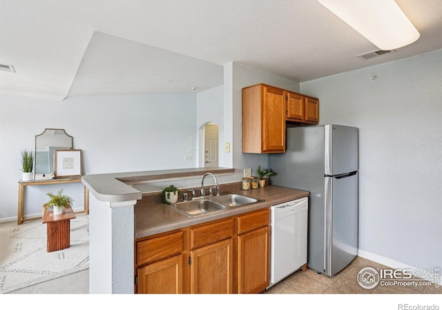 5620 Fossil Creek Pkwy Unit 6303, Fort Collins, CO 80525 - kitchen featuring white dishwasher, arched walkways, a peninsula, brown cabinetry, and freestanding refrigerator
