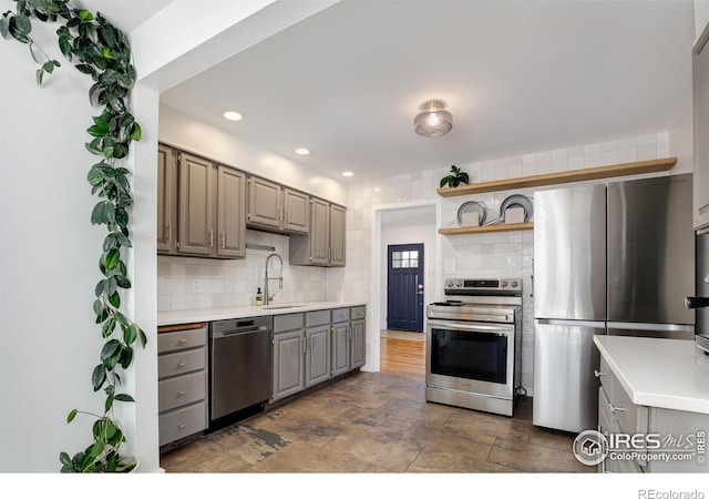 7850 Raleigh Pl, Westminster, CO 80030 - kitchen with appliances with stainless steel finishes, gray cabinetry, open shelves, tasteful backsplash, and light countertops