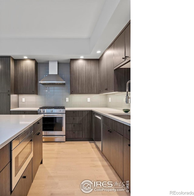2718 Pine St Unit 301, Boulder, CO 80302 - kitchen featuring stainless steel appliances, wall chimney range hood, light wood finished floors, tasteful backsplash, and light countertops