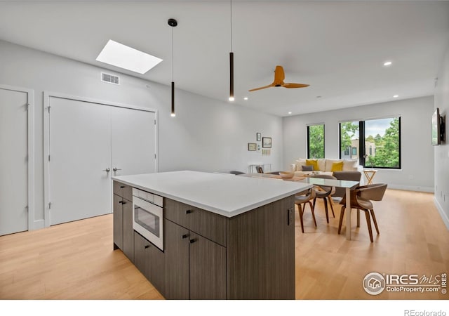 2718 Pine St Unit 301, Boulder, CO 80302 - kitchen with stainless steel microwave, light wood-type flooring, a center island, a skylight, and recessed lighting