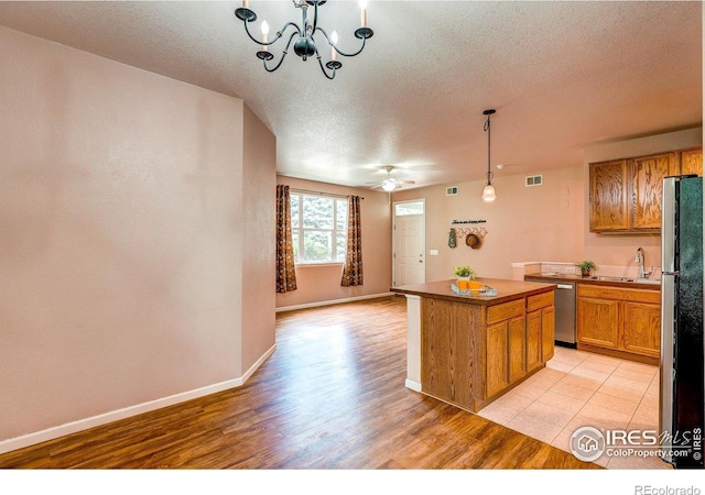 2131 Grays Peak Dr Unit 102, Loveland, CO 80538 - kitchen with a textured ceiling, freestanding refrigerator, a chandelier, light wood-style floors, and open floor plan