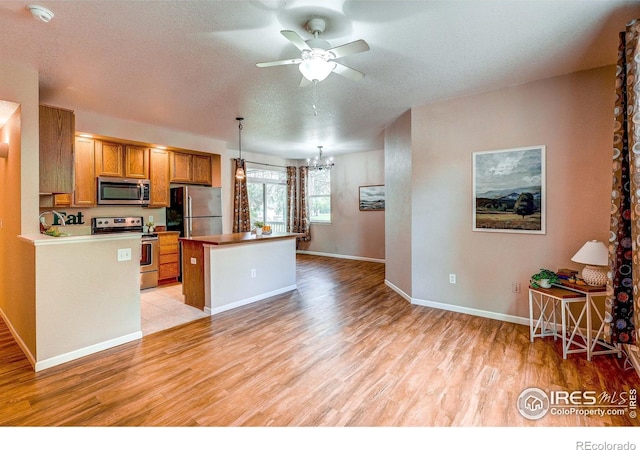 2131 Grays Peak Dr Unit 102, Loveland, CO 80538 - kitchen with stainless steel appliances, ceiling fan, brown cabinets, light wood-style flooring, and a chandelier