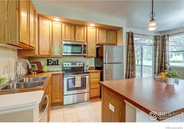 2131 Grays Peak Dr Unit 102, Loveland, CO 80538 - kitchen with appliances with stainless steel finishes, hanging light fixtures, light tile patterned floors, and a textured ceiling