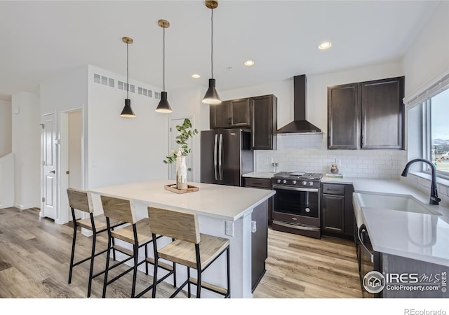 945 Abbott Ln Unit 2, Fort Collins, CO 80524 - kitchen with wall chimney range hood, appliances with stainless steel finishes, a kitchen breakfast bar, light wood-style floors, and recessed lighting