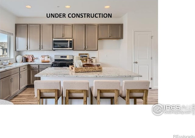 919 Schlagel St Unit 3, Fort Collins, CO 80524 - kitchen featuring stainless steel appliances, light wood-style flooring, decorative backsplash, a breakfast bar, and a center island