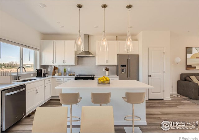 919 Schlagel St Unit 3, Fort Collins, CO 80524 - kitchen featuring wall chimney exhaust hood, appliances with stainless steel finishes, a kitchen island, a kitchen breakfast bar, and dark wood finished floors