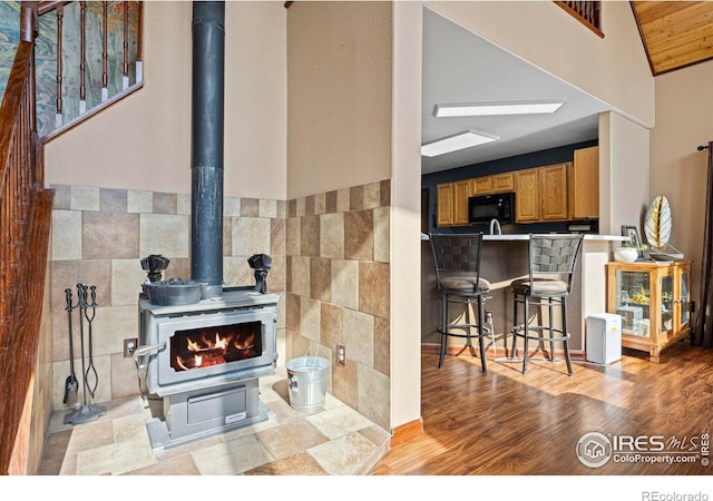 228 Mount Everest Dr, Livermore, CO 80536 - living room featuring a wood stove, wainscoting, wood finished floors, tile walls, and lofted ceiling