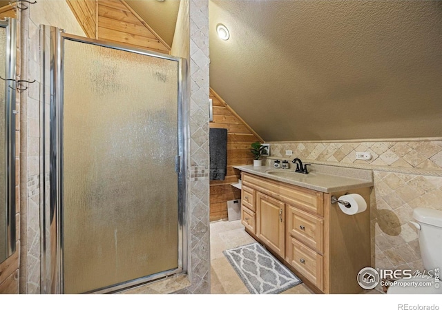 228 Mount Everest Dr, Livermore, CO 80536 - bathroom featuring vaulted ceiling, a stall shower, vanity, a textured ceiling, and wooden walls