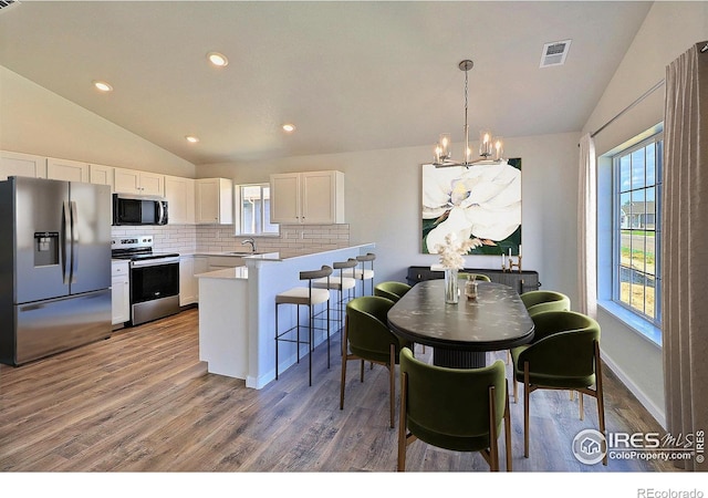 4327 Primrose Ln, Evans, CO 80620 - kitchen with appliances with stainless steel finishes, vaulted ceiling, a chandelier, a peninsula, and tasteful backsplash