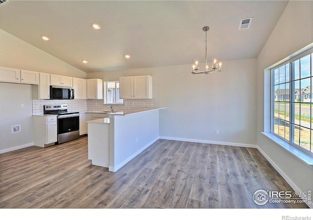 4327 Primrose Ln, Evans, CO 80620 - kitchen featuring appliances with stainless steel finishes, vaulted ceiling, decorative backsplash, a chandelier, and white cabinetry